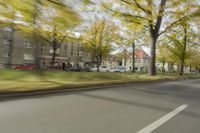 a guy riding his bike down an empty road with lots of trees behind him in a blurry photo