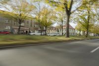 a guy riding his bike down an empty road with lots of trees behind him in a blurry photo