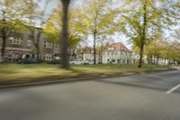 a guy riding his bike down an empty road with lots of trees behind him in a blurry photo