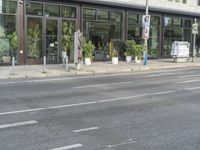 a person riding on the street by a bike outside of a storefront window in front of a street sign with trees