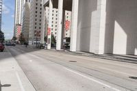 the man is riding his bike down the city street with pedestrians nearby and other cars in front