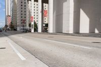 the man is riding his bike down the city street with pedestrians nearby and other cars in front