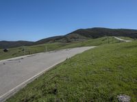 a person on a bike on a mountain road with hills in the background, with an empty roadway next to it