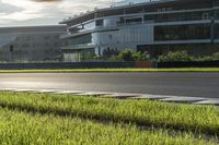 a person is riding their bike on a grass lined road with tall buildings in the background