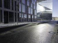 the sun shines through the glass facade and windows above the sidewalk in a city