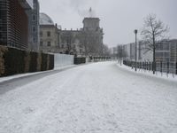 a road with snow covering it next to large buildings on both sides of the street