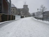 a road with snow covering it next to large buildings on both sides of the street