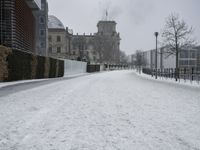 a road with snow covering it next to large buildings on both sides of the street