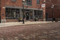 a black and white fire hydrant on a brick road next to buildings with lots of windows