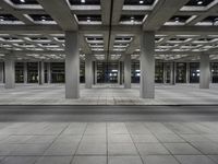 a building with an open walkway and parking meters between it and another parking meter on the right