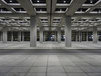 a building with an open walkway and parking meters between it and another parking meter on the right