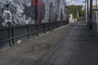 a black and white mural on the side of a building near a walkway with a red light
