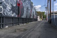 a black and white mural on the side of a building near a walkway with a red light