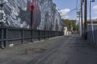 a black and white mural on the side of a building near a walkway with a red light