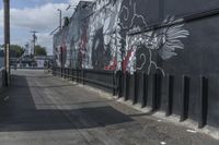 a black and white mural on the side of a building near a walkway with a red light