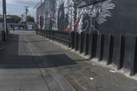 a black and white mural on the side of a building near a walkway with a red light