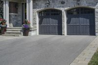 a black and white brick home with dark colored garage doors and flower containers on the front