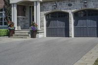 a black and white brick home with dark colored garage doors and flower containers on the front