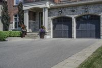 a black and white brick home with dark colored garage doors and flower containers on the front