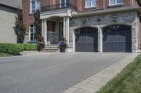 a black and white brick home with dark colored garage doors and flower containers on the front