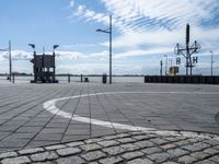 a circle has been drawn in the street by a dock with water behind it and birds flying overhead