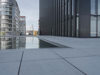 black building reflecting off the water on the edge of a city canal with a man and woman