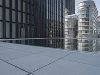 black building reflecting off the water on the edge of a city canal with a man and woman