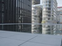 black building reflecting off the water on the edge of a city canal with a man and woman
