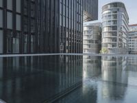 black building reflecting off the water on the edge of a city canal with a man and woman