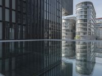black building reflecting off the water on the edge of a city canal with a man and woman
