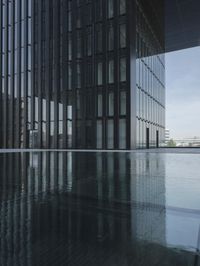 black building reflecting off the water on the edge of a city canal with a man and woman