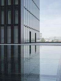 black building reflecting off the water on the edge of a city canal with a man and woman