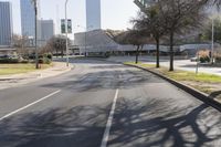 a black car drives along a deserted road in front of the modern building behind it