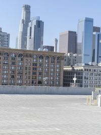 a black car parked on the concrete road in front of a cityscape in a parking lot