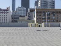 a black car parked on the concrete road in front of a cityscape in a parking lot