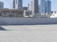 a black car parked on the concrete road in front of a cityscape in a parking lot