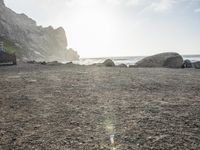 a black dog lying on top of a beach next to the ocean on top of rocks