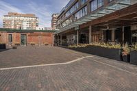 black potted planters sitting on the brick walkway outside a restaurant with tall buildings in the background