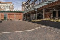 black potted planters sitting on the brick walkway outside a restaurant with tall buildings in the background