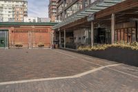 black potted planters sitting on the brick walkway outside a restaurant with tall buildings in the background