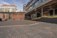 black potted planters sitting on the brick walkway outside a restaurant with tall buildings in the background