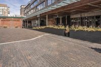 black potted planters sitting on the brick walkway outside a restaurant with tall buildings in the background