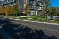 a black road next to an apartment building with grass and trees in front of it