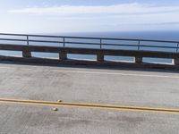 a couple of black skateboards sit on top of a ramp as the ocean sits next to a roadway