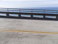 a couple of black skateboards sit on top of a ramp as the ocean sits next to a roadway