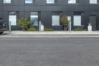 a black suv is parked outside the building next to street signs and trees that are on a sidewalk