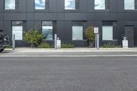 a black suv is parked outside the building next to street signs and trees that are on a sidewalk