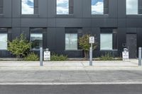 a black suv is parked outside the building next to street signs and trees that are on a sidewalk