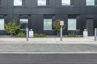 a black suv is parked outside the building next to street signs and trees that are on a sidewalk