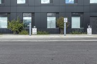 a black suv is parked outside the building next to street signs and trees that are on a sidewalk